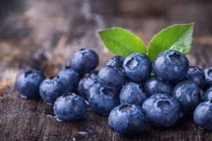 Why is my blueberry compote not thickening? 2 A cluster of fresh, dewy blueberries with vibrant green leaves, placed on a wooden surface.