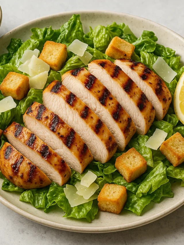 Grilled Chicken Caesar Salad on a plate with romaine, shaved Parmesan, and croutons
