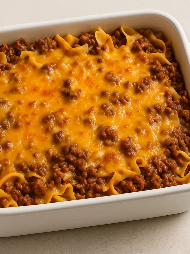 ground beef casserole in a white baking dish with melted cheddar cheese