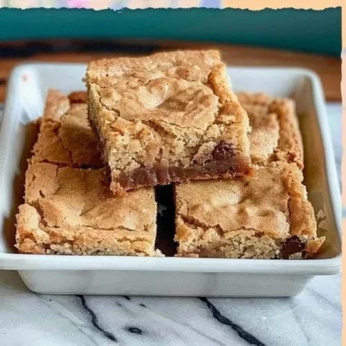 A plate of homemade blondie brownies, thick and chewy with a golden color.