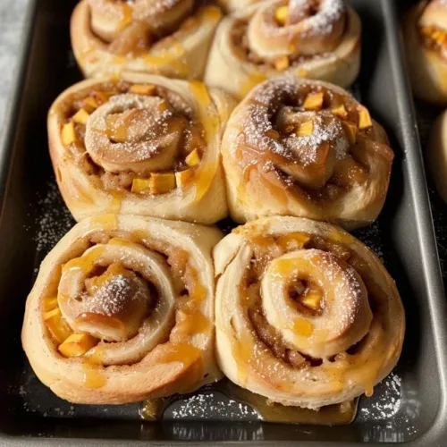 Freshly baked Peach Cobbler Cinnamon Rolls with peach filling and cinnamon glaze.