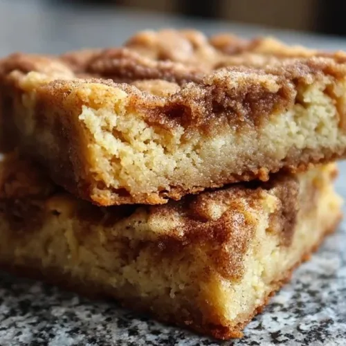 Deliciously chewy snickerdoodle blondies stacked on a plate.