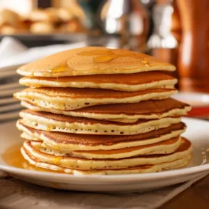 Fluffy sourdough pancakes stack on a plate with syrup and berries