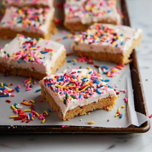Frosted sugar cookie bars topped with colorful sprinkles