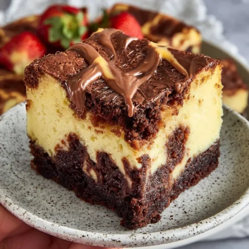 Fudgy chocolate brownie topped cheesecake slice on a plate