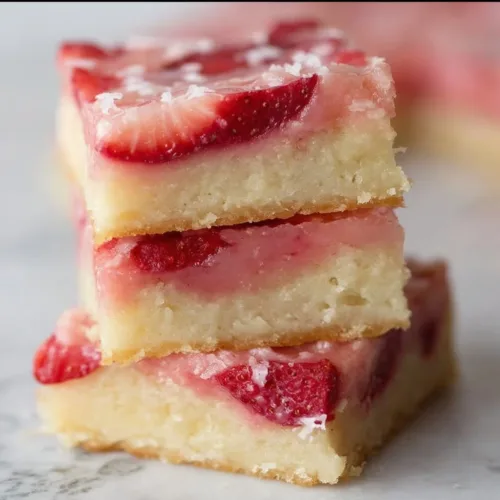 Freshly baked strawberry lemon bars on a plate with mint leaves
