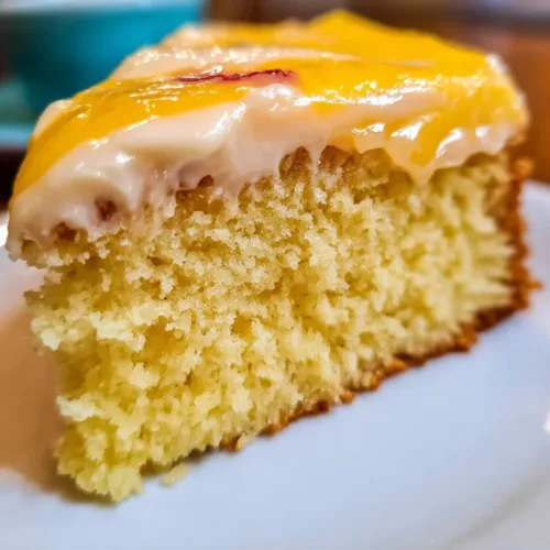 Peach Cake topped with rich brown sugar frosting on a rustic wooden table