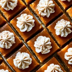 Delicious easy pumpkin pie bars topped with whipped cream on a white plate.