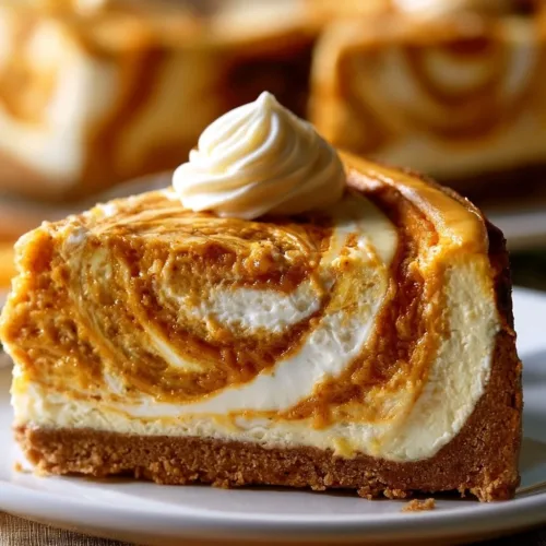 Slice of easy pumpkin swirl cheesecake topped with whipped cream and autumn spices.