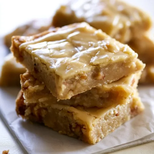 Delicious maple glazed apple blondies on a plate with fresh apples.